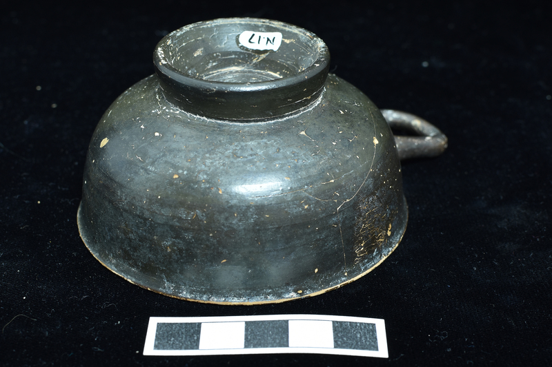 One-handled cup w raised base and single horizontal handle, slightly projecting lip.  Solidly coated