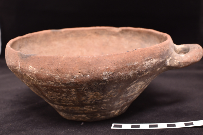 Flat-bottomed bowl with inturned rim and incrusted decoration on exterior.  Primary decoration consists of two broad stripes around lower body above which a row of approximately solidly painted squares and at juncture of body and rim stripe with pendant loops; traces of now largely fugitive X’s in each square.  Traces of stripe on roughly horizontal loop handle of circular section attached just below rim.