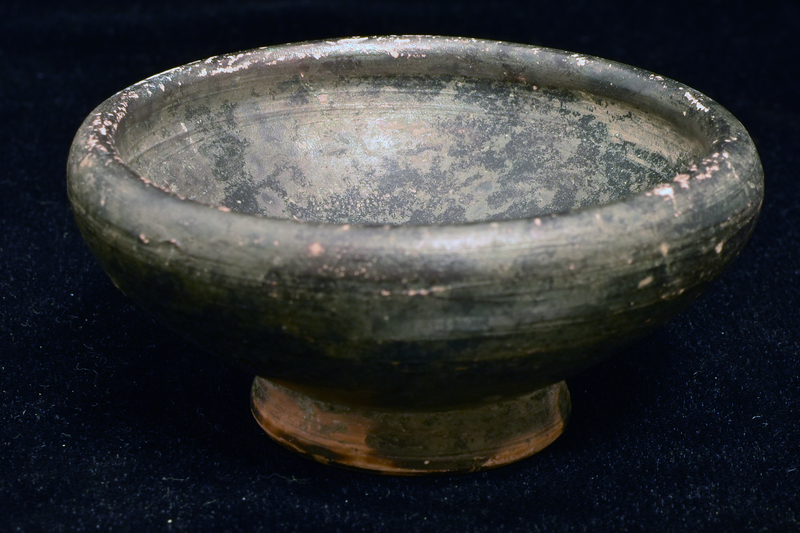 Bowl w shallowly convex sides spreading to rounded shoulder and thick plain rim from ring base w flat center  w whorl where cut from wheel prominent.  Coated all over int and most of ext w dark paint which also splashed on underside of base.