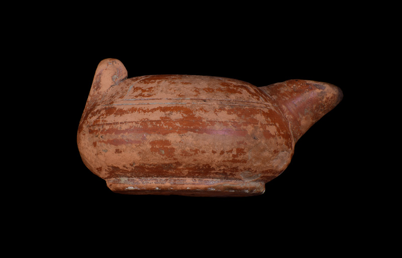 Squat round-carinated body on sharply defined offset base; shallowly concave discus w finely incised line defining it on ext, pairs of similar incised lines on body at mid-nozzle & at base of nozzle.  Opposite nozzle on shoulder horizontal volute handle.  Coated on ext w glossy red slip which darkened at edge of nozzle.  Scratched in base uppercase Alpha,  Gamma, Iota.