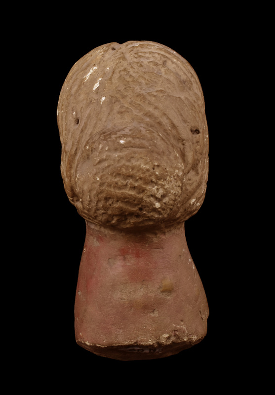 Head and neck of female with wig-like hair parted in middle and pulled back into a bun, hair strands marked by broad sawtooth impressions.  Flat oval face projecting forward with plastic eyes with pupils incised, prominent nose with nostrils indicated, and with horizontal mouth slit on raised surface indicating lips, upper lip with slight horizontal depression at center.  Thick neck spreading toward break, possibly not attached to a body but some kind of base.  Flesh painted reddish, hair showing traces of white paint which is better preserved on forehead in front of hair mass.