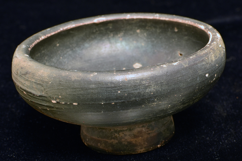 Convex-sided bowl w distinct inward curve to thick rim in upper portion; high ring base with prominent nipple in center of underside.  Coated all over w dark paint.