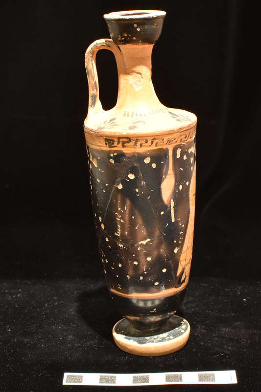 Trumpet-mouthed lekythos, w main decoration opposite handle woman pouring libation over altar wearing chiton & himation with sakkos on head;  meander band above, reserved stripe below. Lower body  and surface of foot solidly coated.  Shoulder decorated with 4 vertical palmettes; short stripes radiating from base of neck; exterior and interior of mouth & exterior of handle solidly coated.