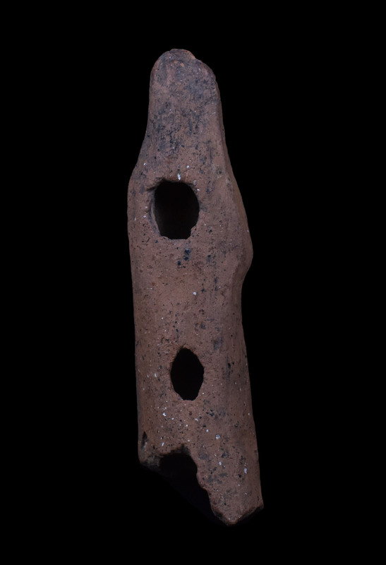 Mouldmade standing figure w palla draped over head and falling on either side, pulled across body diagonally over r arm; l arm at side holding vertical clump of drapery; slightly projecting right knee.  Pinched ridge of clay articulating face.  2 large vent holes in back.