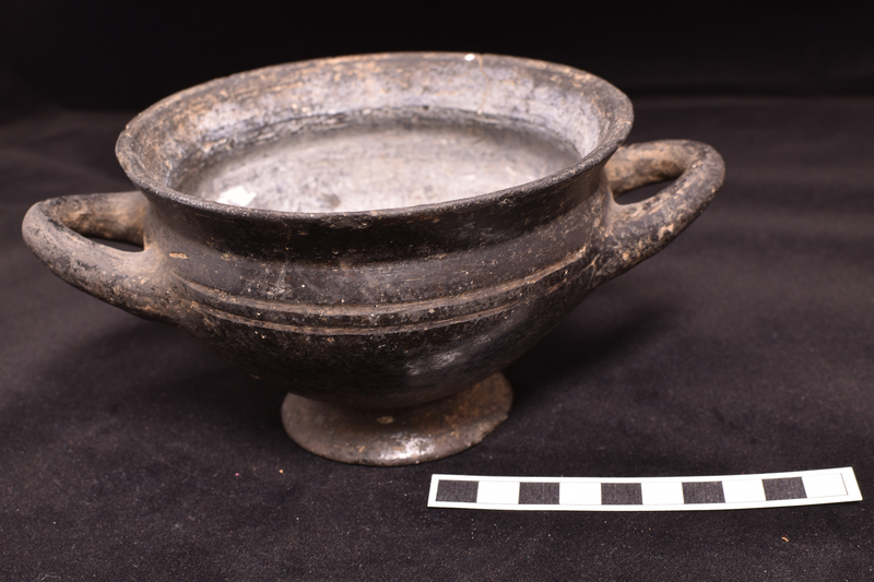Bowl with incurving shoulder & tall flaring rim on short pedestal base;  slightly uptilted handles attached at shoulder.  Two incised horizontal bands on shoulder.  Burnished interior and exterior.