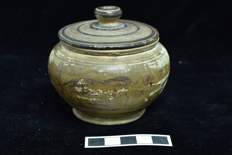 N.8a: Low convex-bodied pyxis w primary decoration on body  between narrow  stripes: heraldic sphinxes on either side of incised staff with two stars above , another below; at rear grazing deer and lion; blob rosettes in field;  figures and rosettes  decorated with incision; low flaring base decorated with dark stripe on bottom edge. N.8b: Lid, probably not belonging, fairly flat with conical handle, decorated with  narrow concentric stripes with top of handle solidly coated.