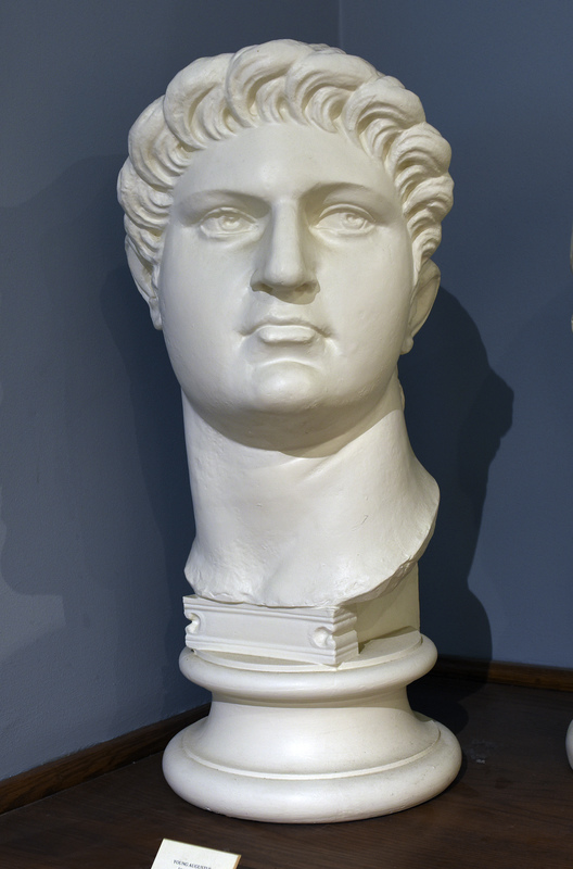 Cast based on an original in the British Museum. Nero Claudius Caesar, born in Antium in 37 to Gnaeus Domitius Ahenobarbus and Agrippina the Younger, was one of Rome’s most intriguing emperors. His mother was the fourth wife of the emperor Claudius and she persuaded him to adopt her son Nero. Agrippina’s malicious intentions were to kill Claudius so that her son would attain the position of emperor, so upon Claudius’ untimely death, seventeen-year-old Nero ascended to the throne in the year 54.

Nero’s personal accomplishments were numerous: he played the lyre, sang, recited his own poetry, competed in the Olympic games, and enjoyed painting and sculpture. Nero is most remembered by the quote, “Nero fiddled while Rome burned,” which may hold some truth. Apparently after a devastating fire ravaged the city of Rome in 64, Nero took the opportunity to displace citizens and build a grand palace for himself called the Domus Aurea in the center of the city. By this time Nero was out of control, and in 65, many high ranking Romans planned the Pisonian conspiracy: a plot to assassinate Nero and name Gaius Calpurnius Piso as the new emperor. Nero unfortunately discovered their plans and put many people to death including his tutor Seneca. Many people died at the hands of Nero throughout his reign including his wife Poppaea, his mother Agrippina, and countless others. The extremely unpopular emperor eventually died at the age of thirty-two after committing suicide in the year 68, “reputedly lamenting, ‘What an artist dies with me!” (Hornblower and Spawforth, 1038).

Nero’s portraiture is rather hard to study chronologically since so many of his portraits were destroyed or defaced after his death. Many coins have survived that show Nero as the emperor, but less then 25 sculptures remain and most of them depict Nero in his youth. His physical characteristics include, “high cheekbones, fleshy jaw and neck, and a full head of tousled hair that is brushed from the crown of his head, low on the forehead,” (Kleiner 136). In later sculptures, like this replica at the Wilcox collection, which depicts Nero at about thirty years of age, his features are primarily the same as those in his youth with one exception: In these busts, his hair is styled in such a way that his wavy hair is culed tightly, especially around his face, and these curls are pushed up forming a wave or crown over his forehead. Nero’s portraits are interesting because although Nero was young when he died, his portraiture reflects the aging process and his differing psychological states as he matures from a boy with youthful exuberance to a paranoid megalomaniac.