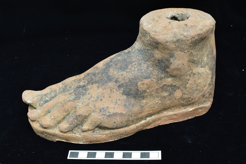 Hollow left foot to just above ankle bone, with toes with joints clearly articulated, toenails poorly articulated; on low base. Top surface shallowly convex with hole in center.