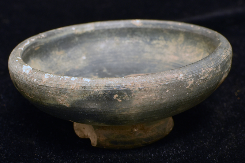 Convex-sided bowl w high max D just below rim, fairly high ring base w deeply concave underside w prominent nipple.  Coated all over w dark paint.