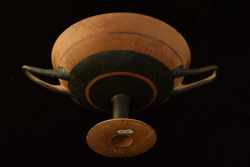 Bowl w slightly uptilted handles on high pedestal foot. Pedestal solidly coated, lower half of  ext bowl decorated w two broad stripes divided by narrow reserved band; upper half divided by narrow painted stripe; handles coated on ext.  Int rim decorated w narrow concentric stripes, bowl solidly coated except for reserved circle in center w narrow concentric stripes in center.