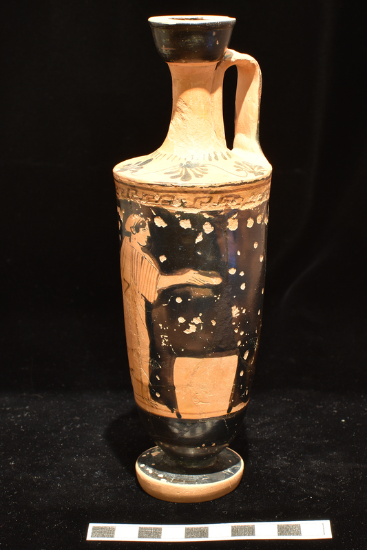 Trumpet-mouthed lekythos, w main decoration opposite handle woman pouring libation over altar wearing chiton & himation with sakkos on head;  meander band above, reserved stripe below. Lower body  and surface of foot solidly coated.  Shoulder decorated with 4 vertical palmettes; short stripes radiating from base of neck; exterior and interior of mouth & exterior of handle solidly coated.