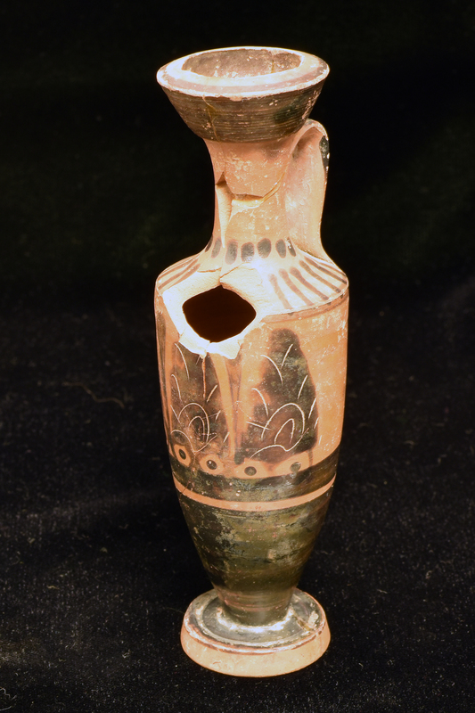 Trumpet-mouthed lekythos w int mouth totally coated, ext mouth coated except on int edge of lip; at base of neck row of blobs, v stripes on shoulder; lower body & top surface of foot solidly coated; upper half of body decorated opposite handle w three upright palmettes w rudimentary incision separated by two vertical leaves, each palmette resting on pair of owl-eye-like elements representing volutes; below palmettes broad horizontal stripe and narrow reserved stripe. Band handle coated on ext fr edge of shoulder to top of neck.