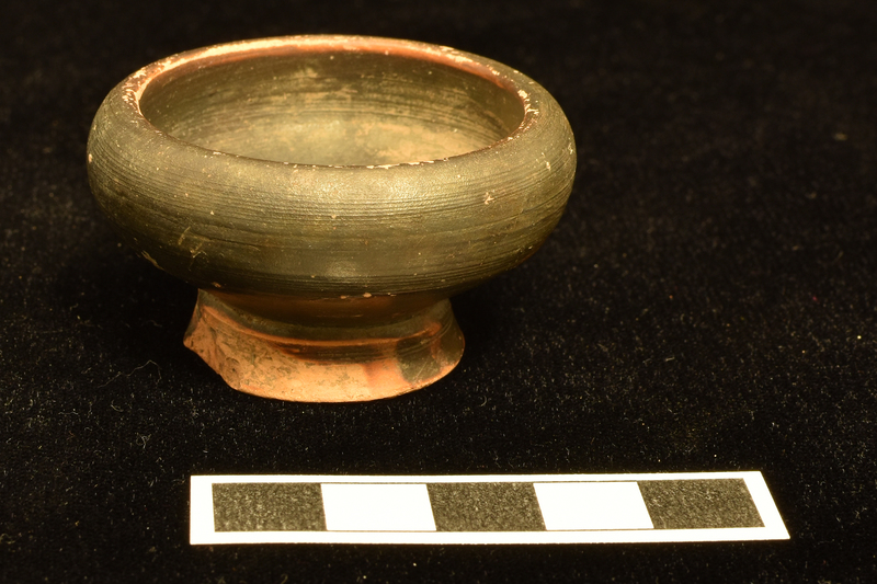 Bowl w incurving rim on low pedestal foot.  Coated inside and out except or underside of base.