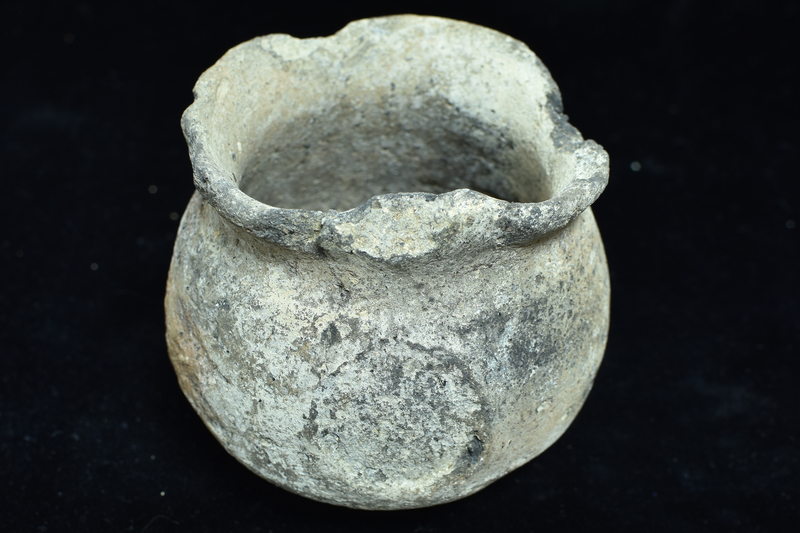 Very coarse globular cup w faint carination just below mid-height, poorly articulated flat base; low out-turned rim; vertical handle attached on upper body to top of rim.
