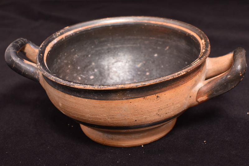 Rounded bowl on thick ring base with small out-turned rim handles of section varying from circular to elliptical attached at maximum diameter.  Interior completely coated except for reserved circle in base and reserved band at inner edge of rim; rim coated on top with continuation of paint to broad stripe at top of exterior; central section reserved except for exterior handles; below handles one narrow and one broad band; on under side of base inner side of base coated with paint extending on to base as broad stripe, small annulus of paint in center.