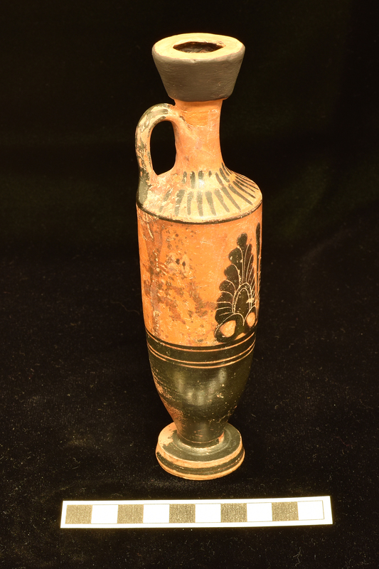 Trumpet- mouthed lekythos with main zone decorated with three upright palmettes opposite handle with slender leaf between and to right of palmette at right; below broad stripe flanked by two narrow stripes lower body totally coated, stripe in center of exterior of foot; single stripe at juncture of body and shoulder above which lower band of longer stripes upper band of vertical stripes and back of handle solidly coated.
