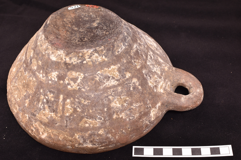Flat-bottomed bowl with inturned rim and incrusted decoration on exterior.  Primary decoration consists of two broad stripes around lower body above which a row of approximately solidly painted squares and at juncture of body and rim stripe with pendant loops; traces of now largely fugitive X’s in each square.  Traces of stripe on roughly horizontal loop handle of circular section attached just below rim.