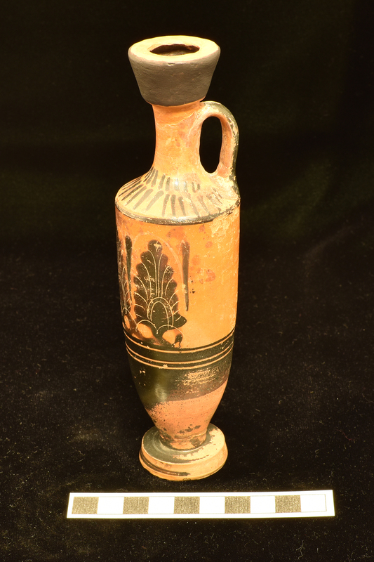 Trumpet- mouthed lekythos with main zone decorated with three upright palmettes opposite handle with slender leaf between and to right of palmette at right; below broad stripe flanked by two narrow stripes lower body totally coated, stripe in center of exterior of foot; single stripe at juncture of body and shoulder above which lower band of longer stripes upper band of vertical stripes and back of handle solidly coated.